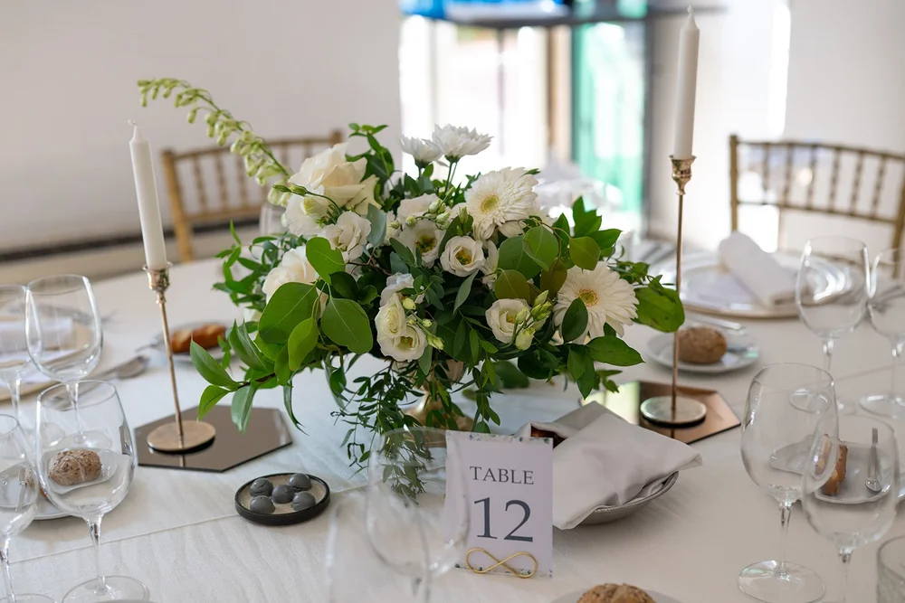 Reception table with white flowers, a table number and place settings