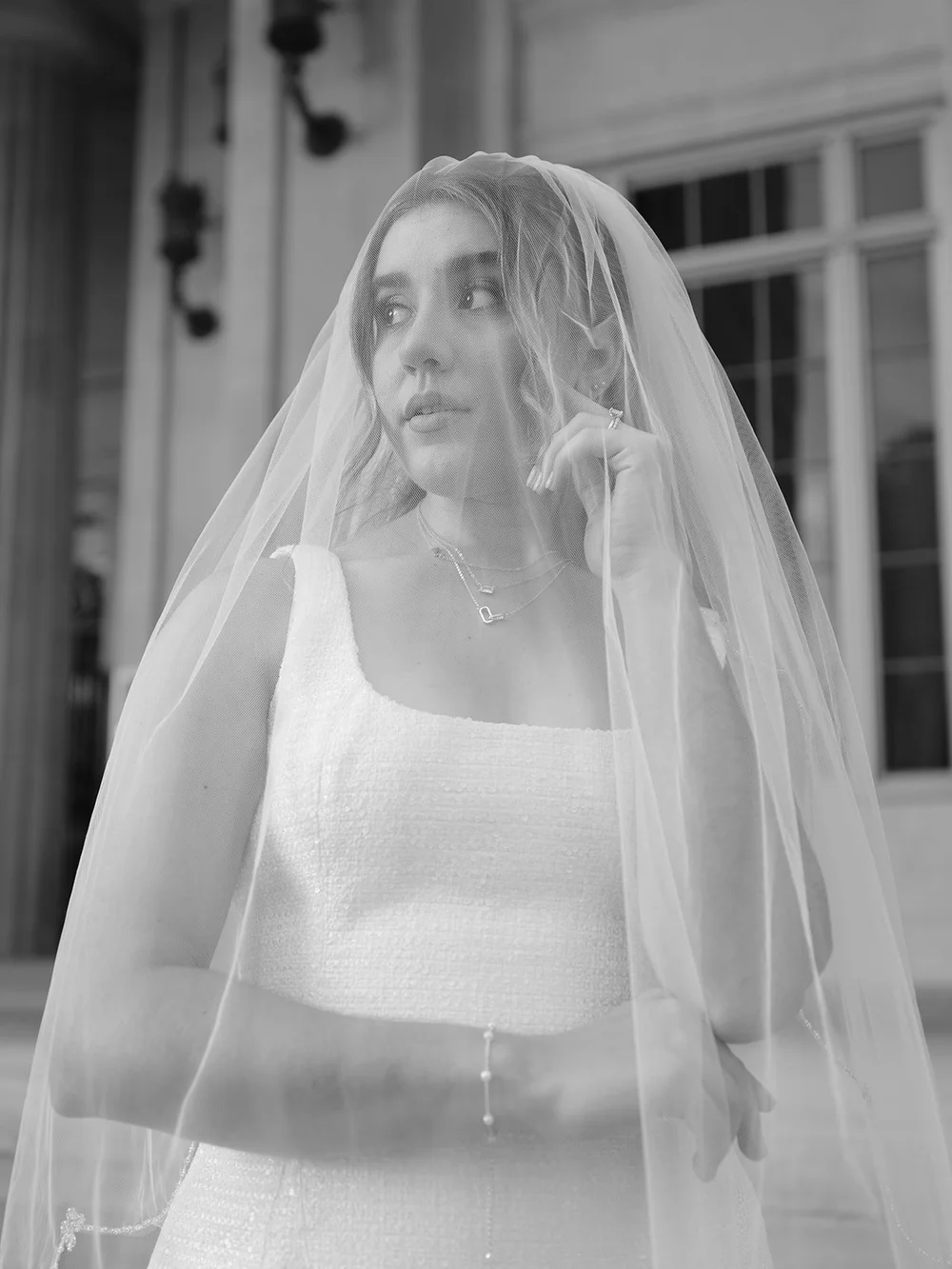 Black and white portrait of the bride in a sheer veil looking off to the side