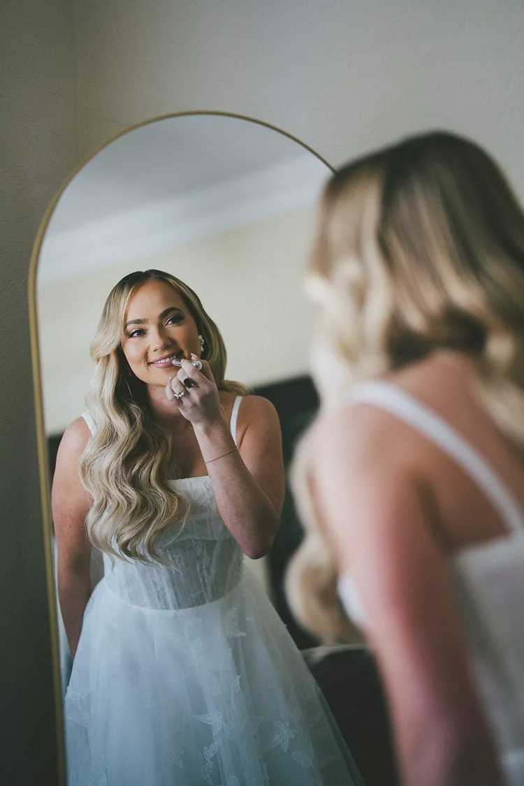 Film photo of Jane in her wedding dress looking in a mirror while another woman stands beside her