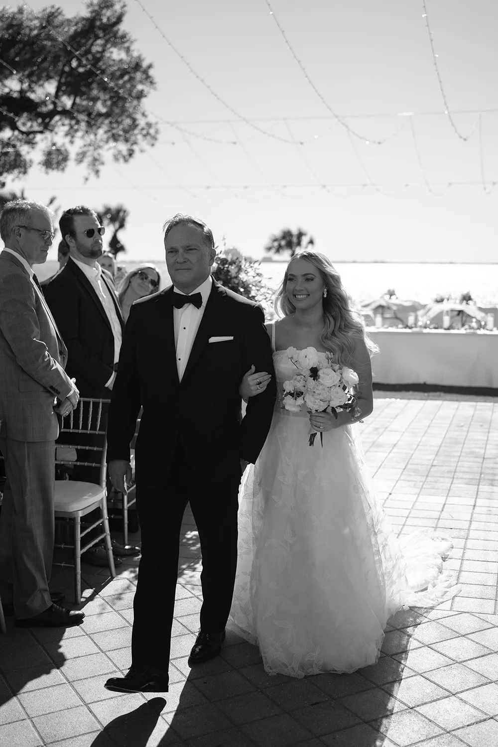 Black and white photo of Jane walking down the aisle toward the water on the terrace