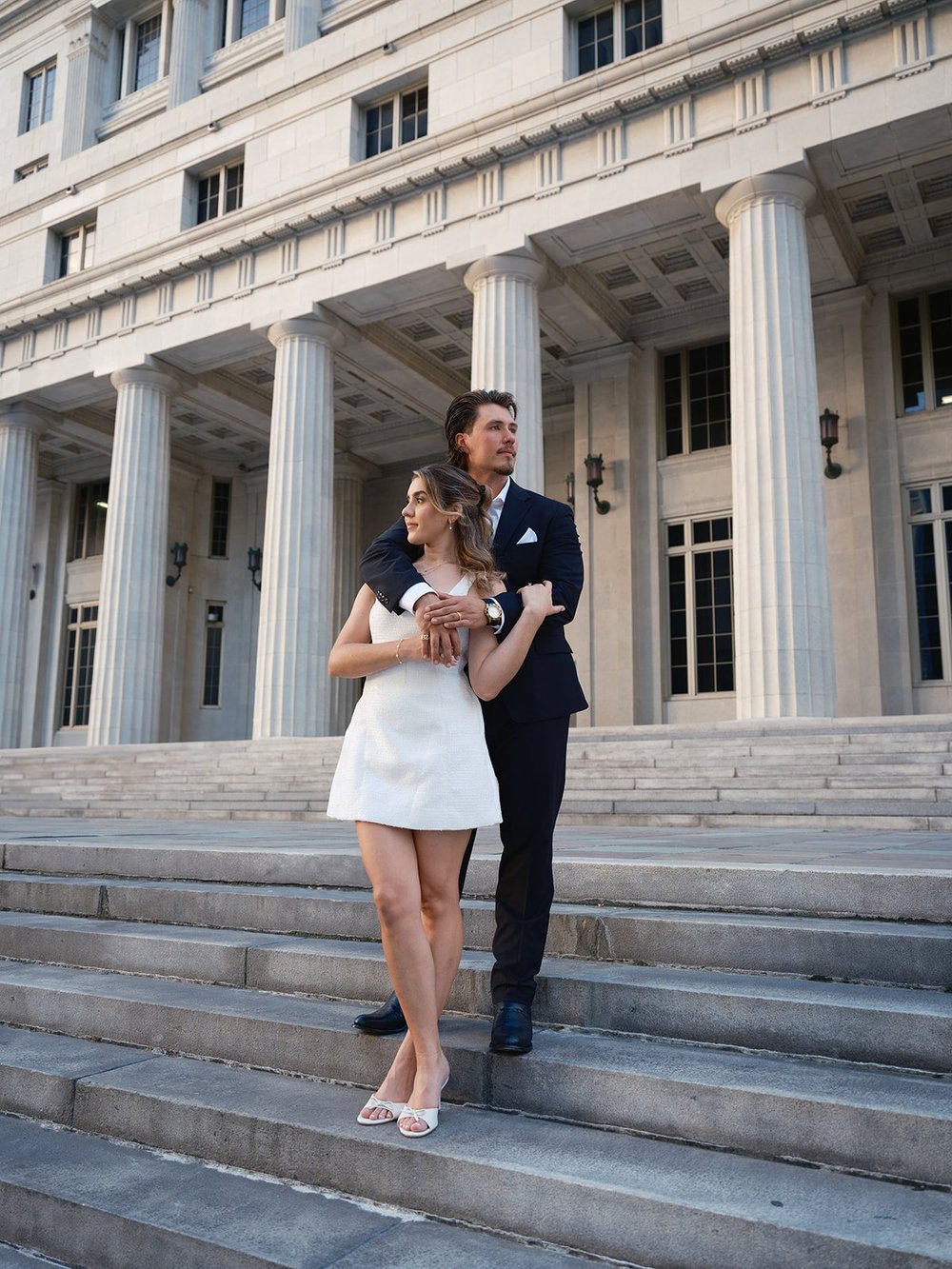 Bride and groom standing together on the courthouse steps below the columns