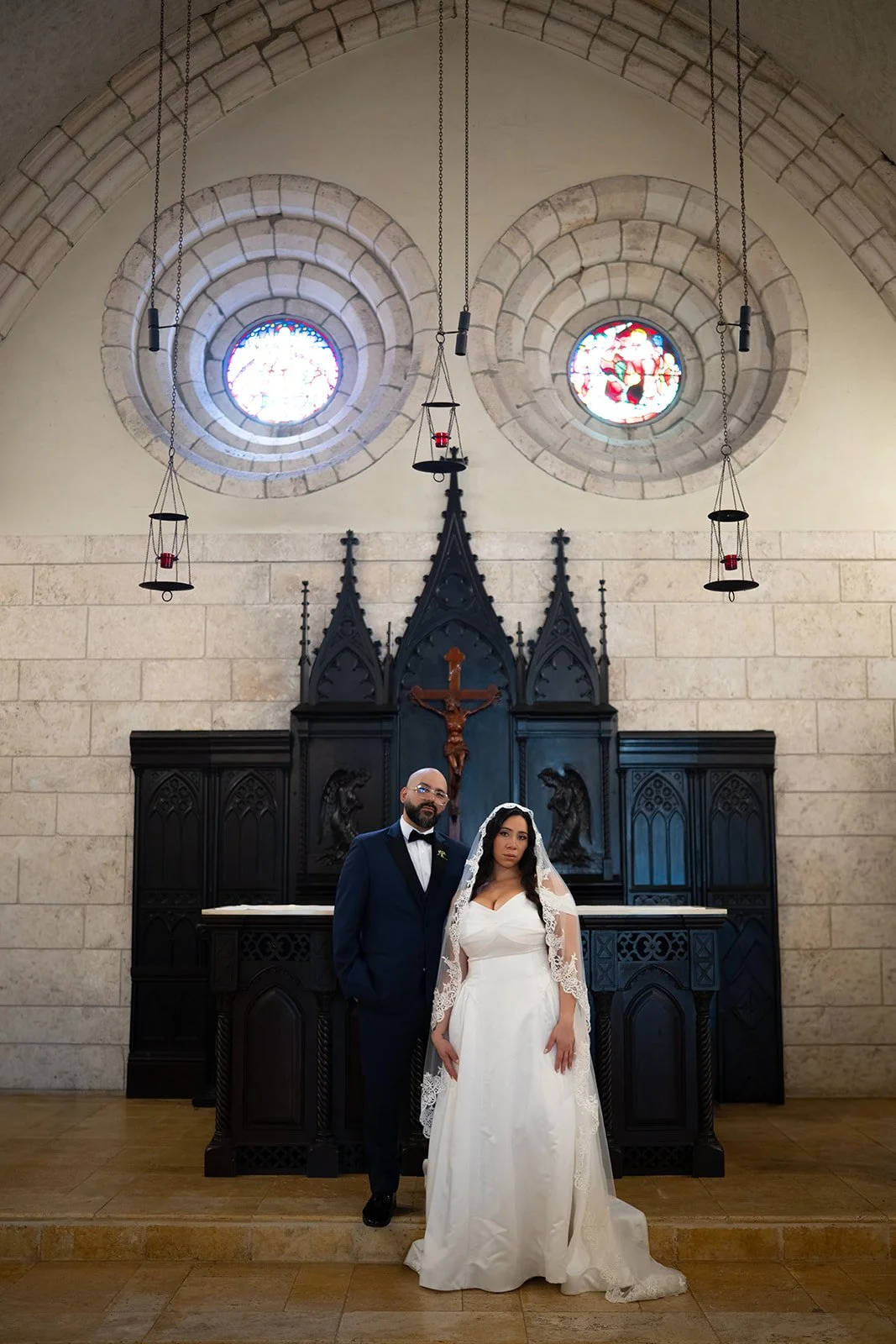 Maria and Christian standing at the chapel altar under two round rose windows at the Ancient Spanish Monastery