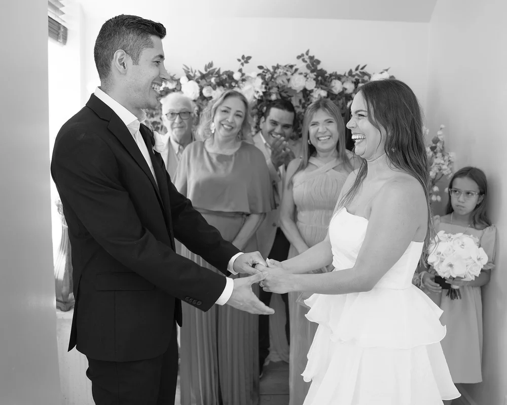 Black and white photo of Chris and David facing each other and holding hands with guests standing behind them