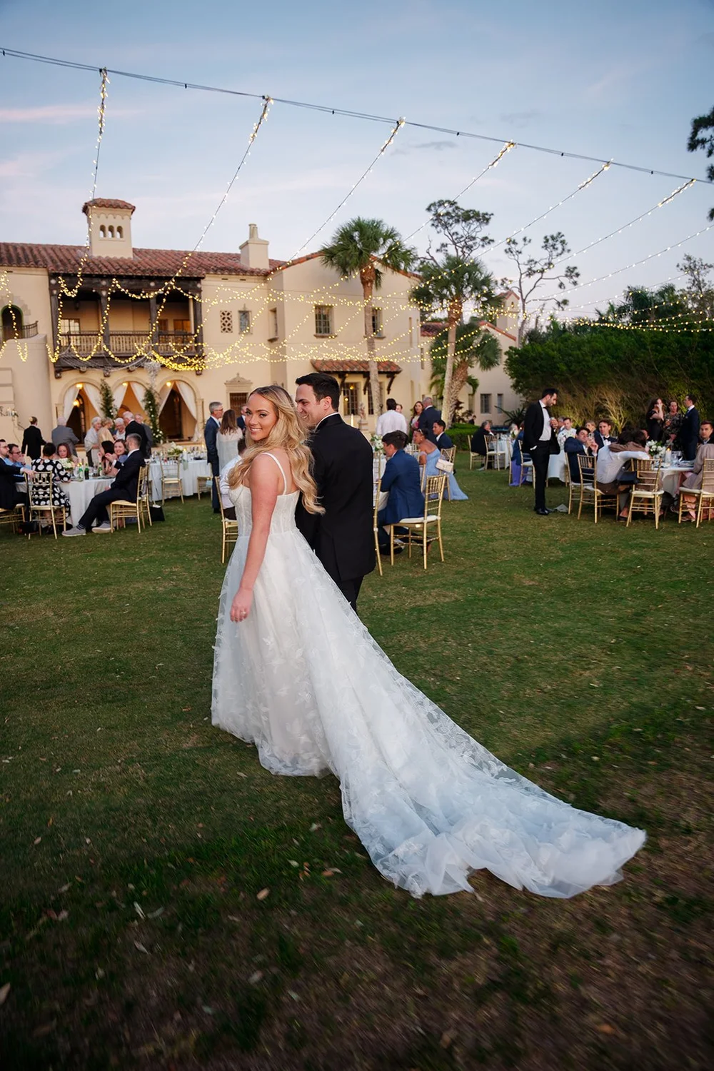 Jane walking across the lawn in her wedding dress, with the Powel Crosley Estate house and reception tables behind her