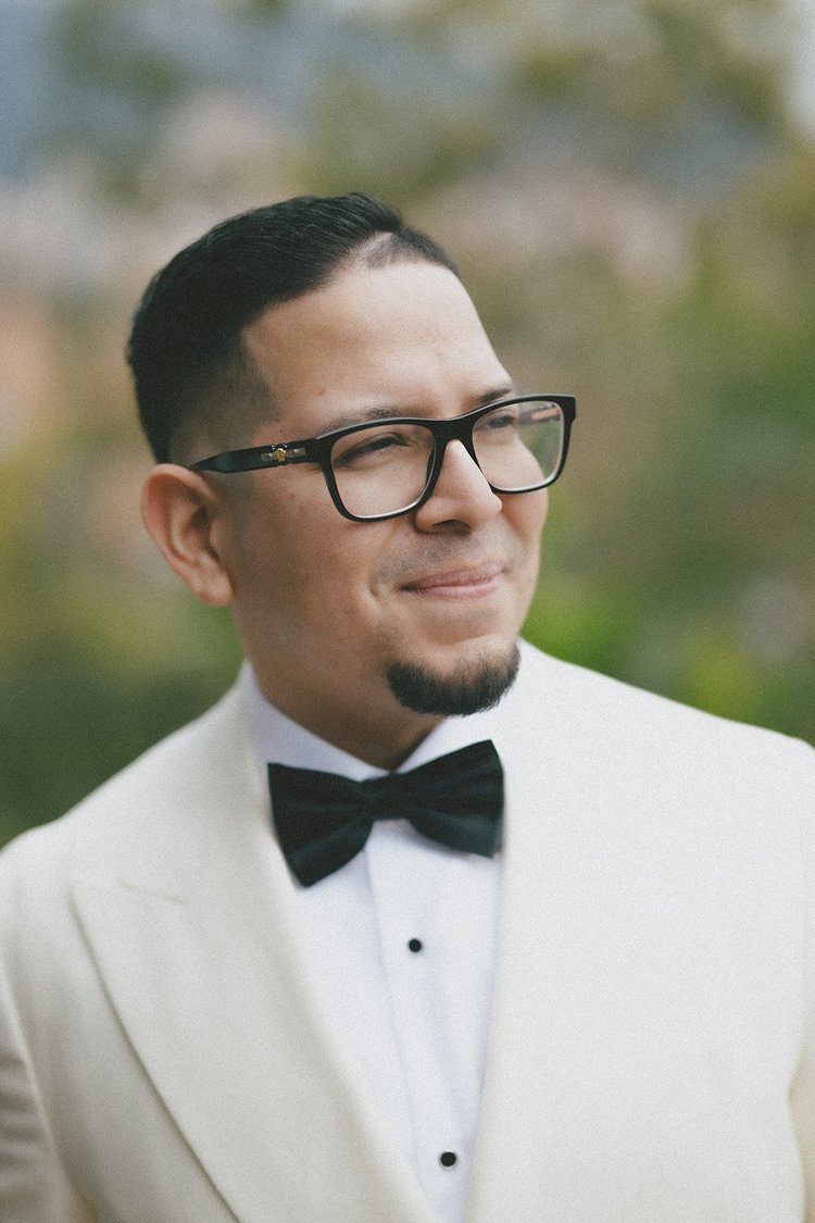 Film photo of Douglas smiling in a cream dinner jacket and black bow tie, wearing glasses
