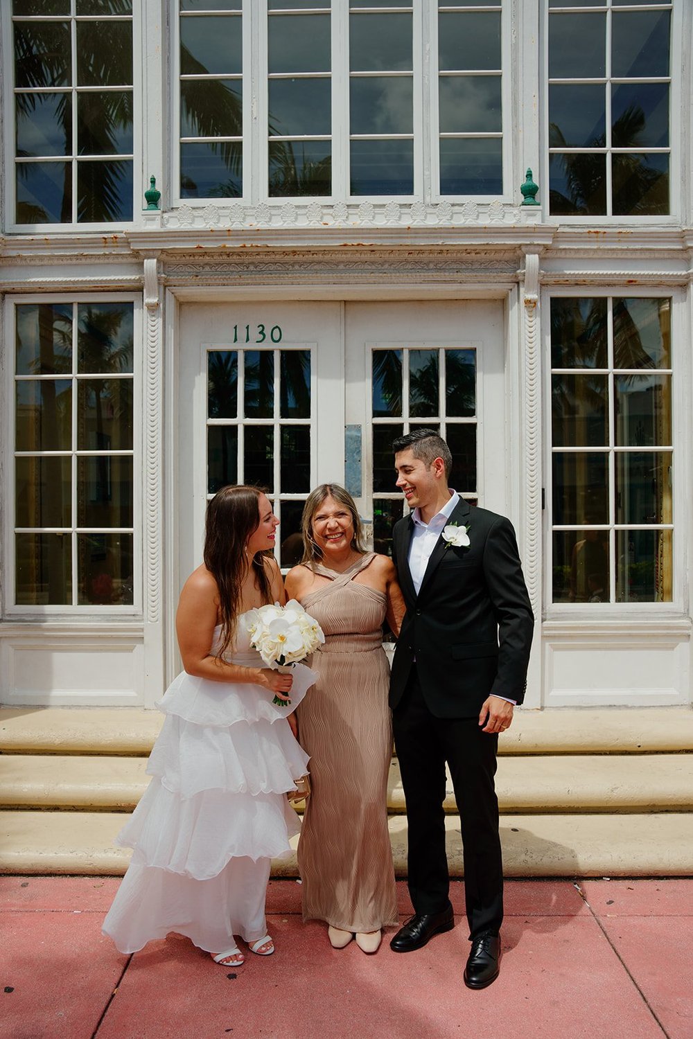 Chris and David with guests on the steps in front of tall glass doors, with a red-pink walkway below