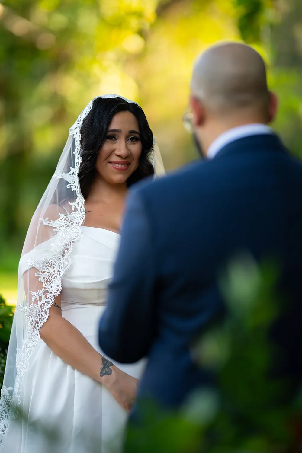 Maria in her lace veil looking at Christian during the ceremony