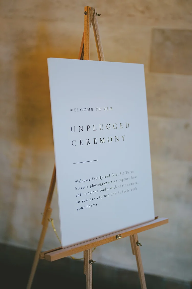 Film photo of a sign on an easel that reads Unplugged Ceremony
