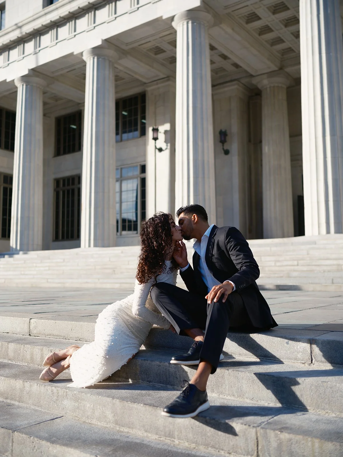 Victoria and Daniel kissing on the steps of the old Miami-Dade County Courthouse, with tall columns behind them, for their Miami-Dade courthouse wedding photos