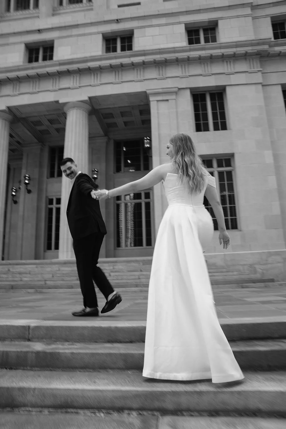 Rachel reaching toward Austin on the courthouse steps in a black and white photo