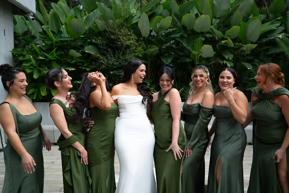Krystine with her bridesmaids in green dresses among tropical plants