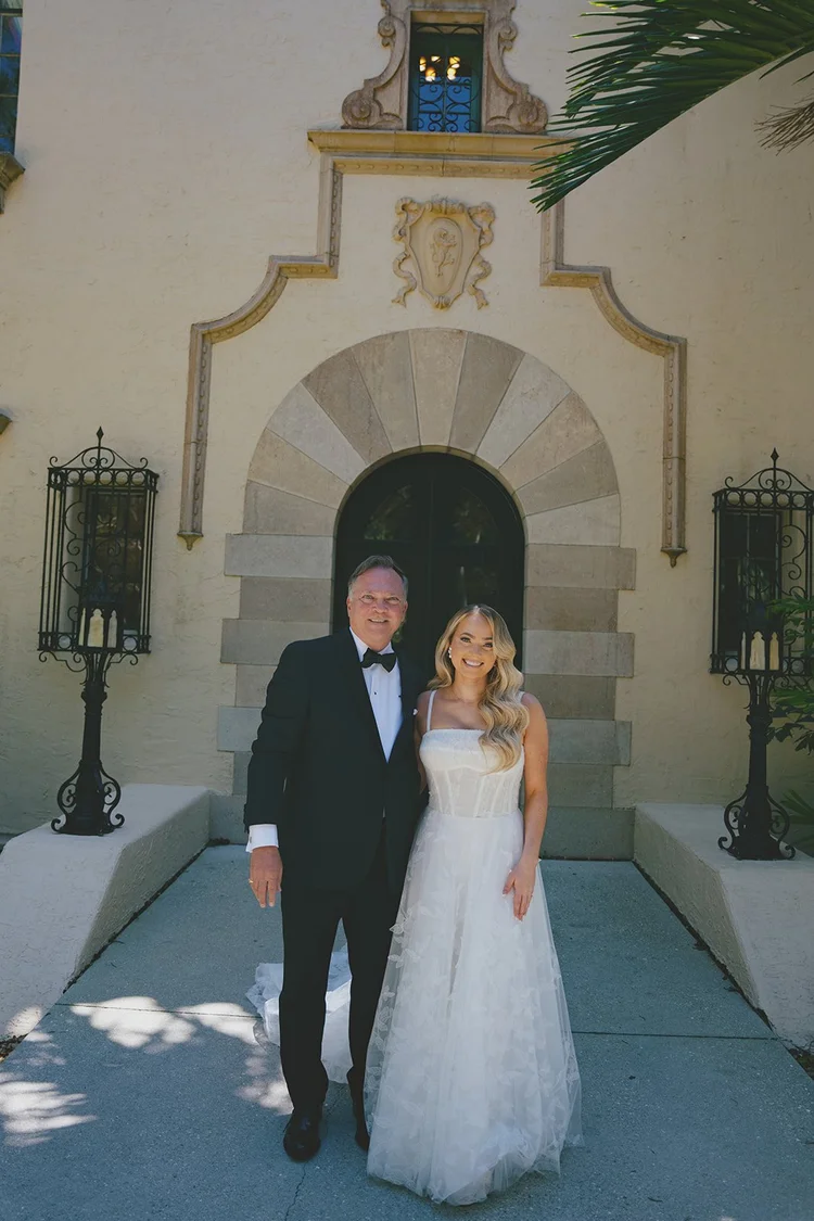 Film photo of Jane and a man in a tuxedo standing in front of an arched doorway with lanterns