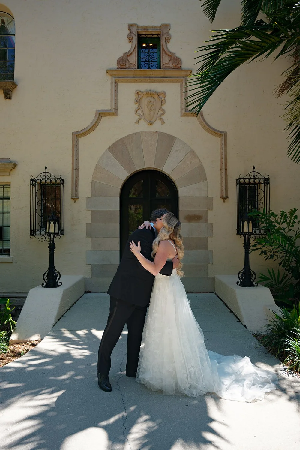 Jane and a man in a tuxedo embracing in front of an arched doorway with lanterns