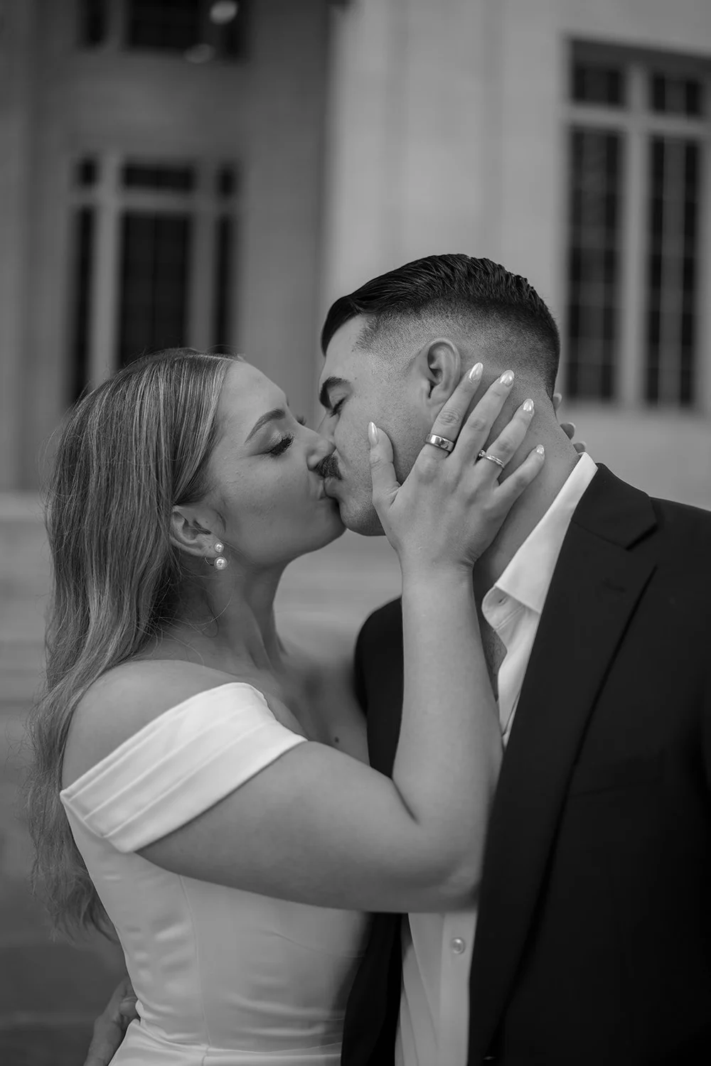 Rachel holding Austin's face as they kiss, a close black and white portrait