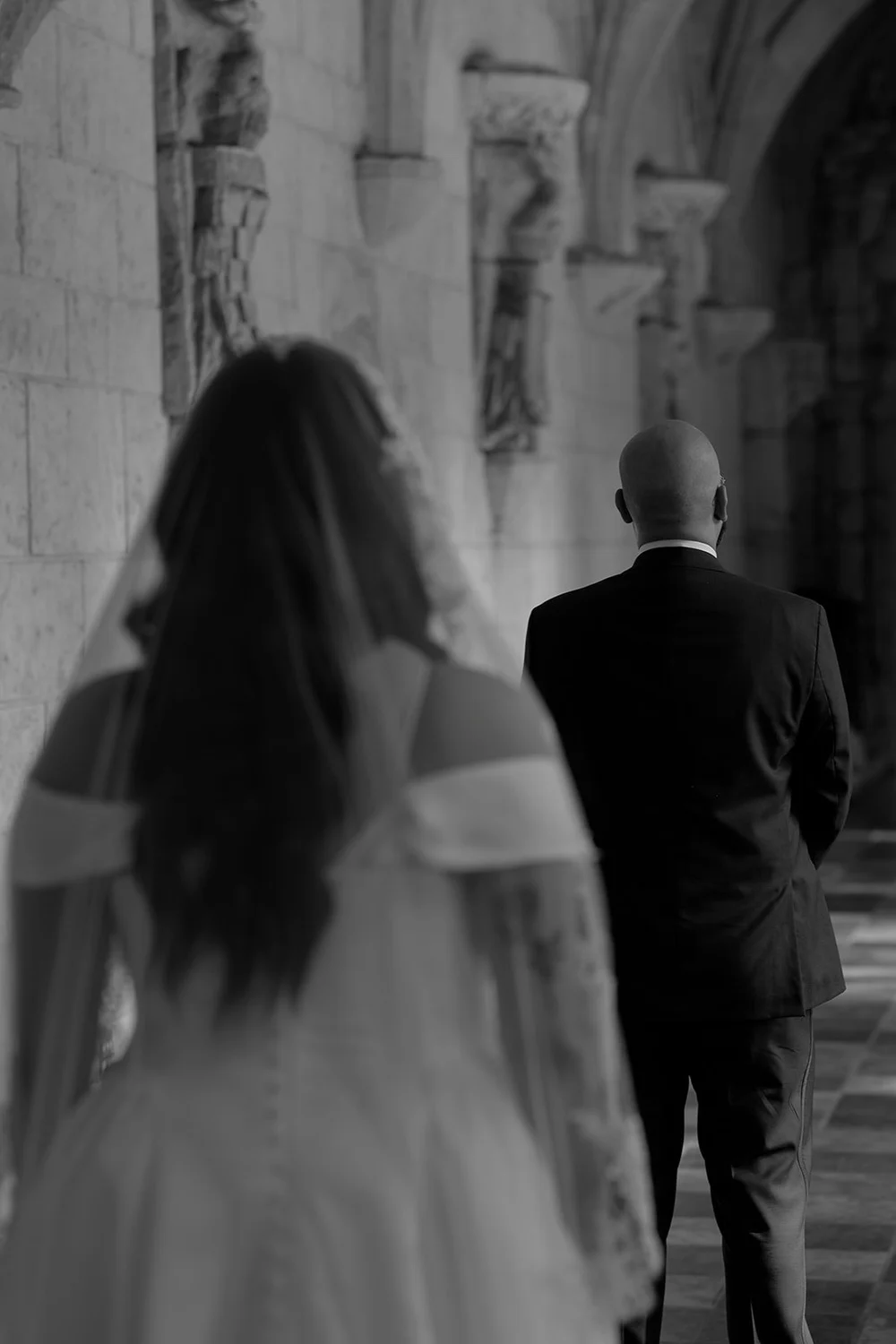 Maria walking up behind Christian in the cloister, in black and white