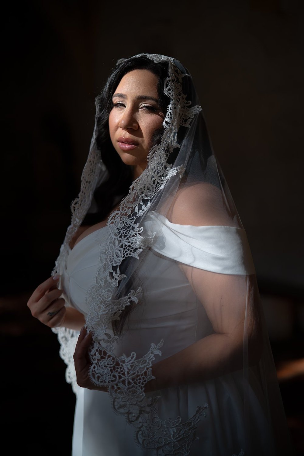 Moody portrait of Maria in her lace veil with soft light on one side
