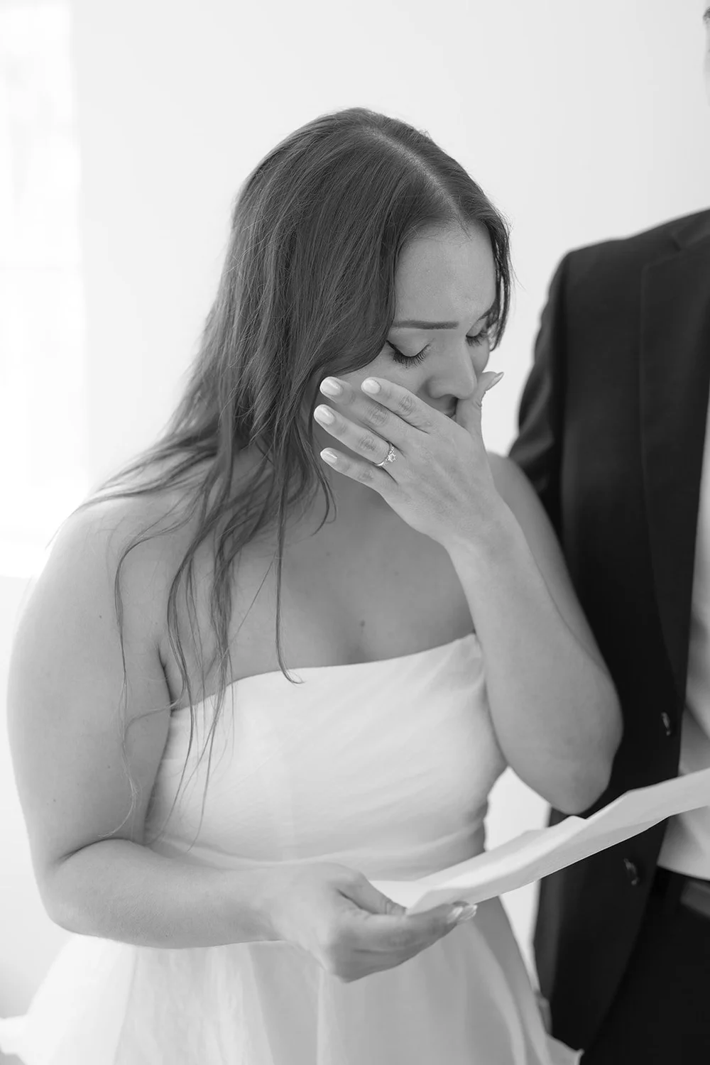 Black and white photo of Chris wiping a tear while holding a sheet of paper