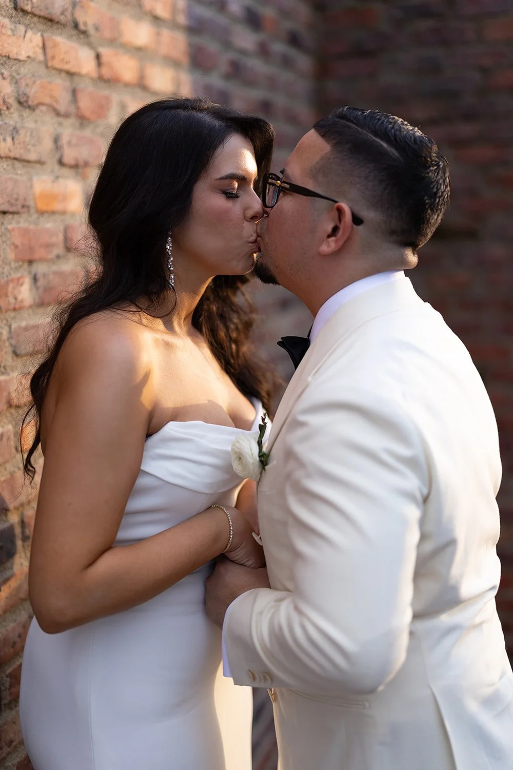 Krystine and Douglas kissing in front of a brick wall