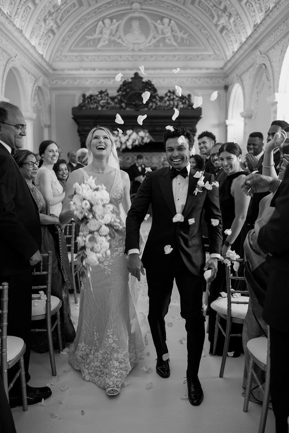 Black and white photo of Ellen and Jacob walking up the aisle between guests
