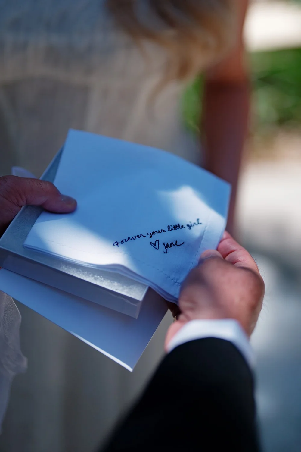Close-up of hands holding a blue envelope with a handwritten note
