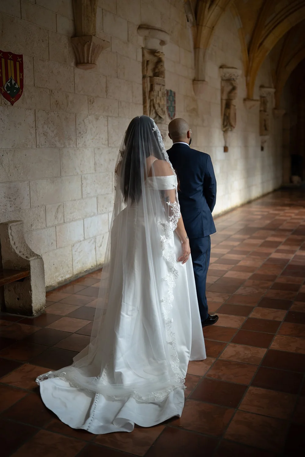 Maria in her white gown and long veil walking along the cloister toward Christian
