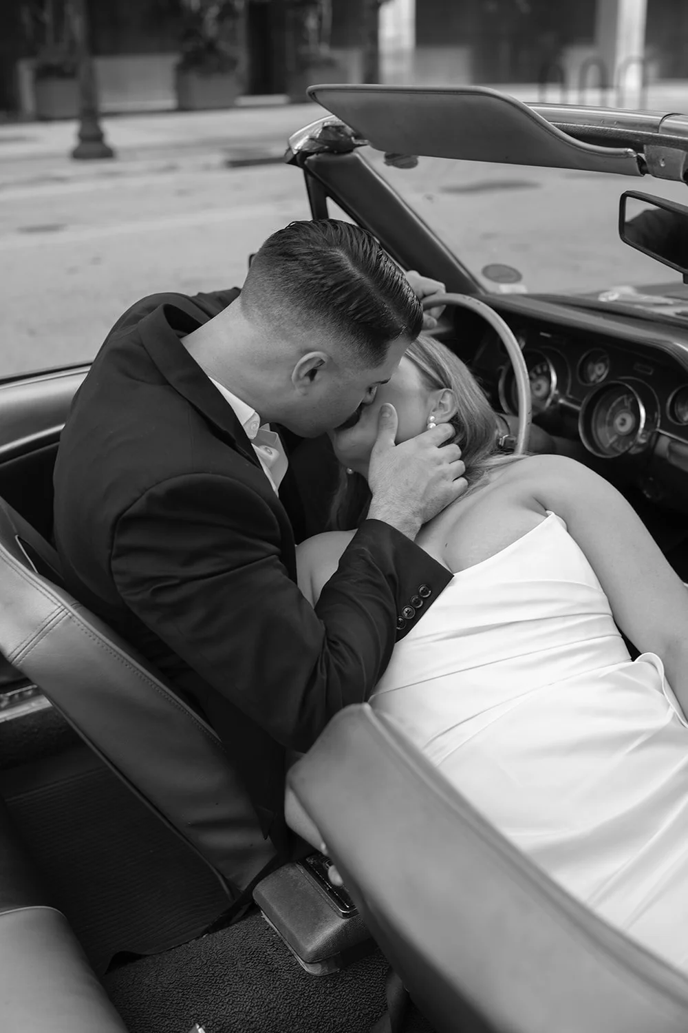Austin kissing Rachel as they sit in the Mustang convertible, in black and white