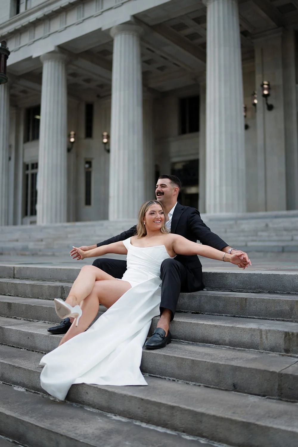 Rachel leaning back with her arms out on the courthouse steps next to Austin