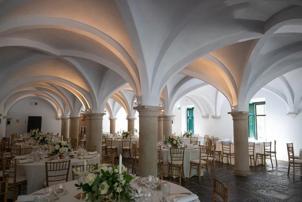 Reception room with white vaulted stone arches and round tables set for dinner