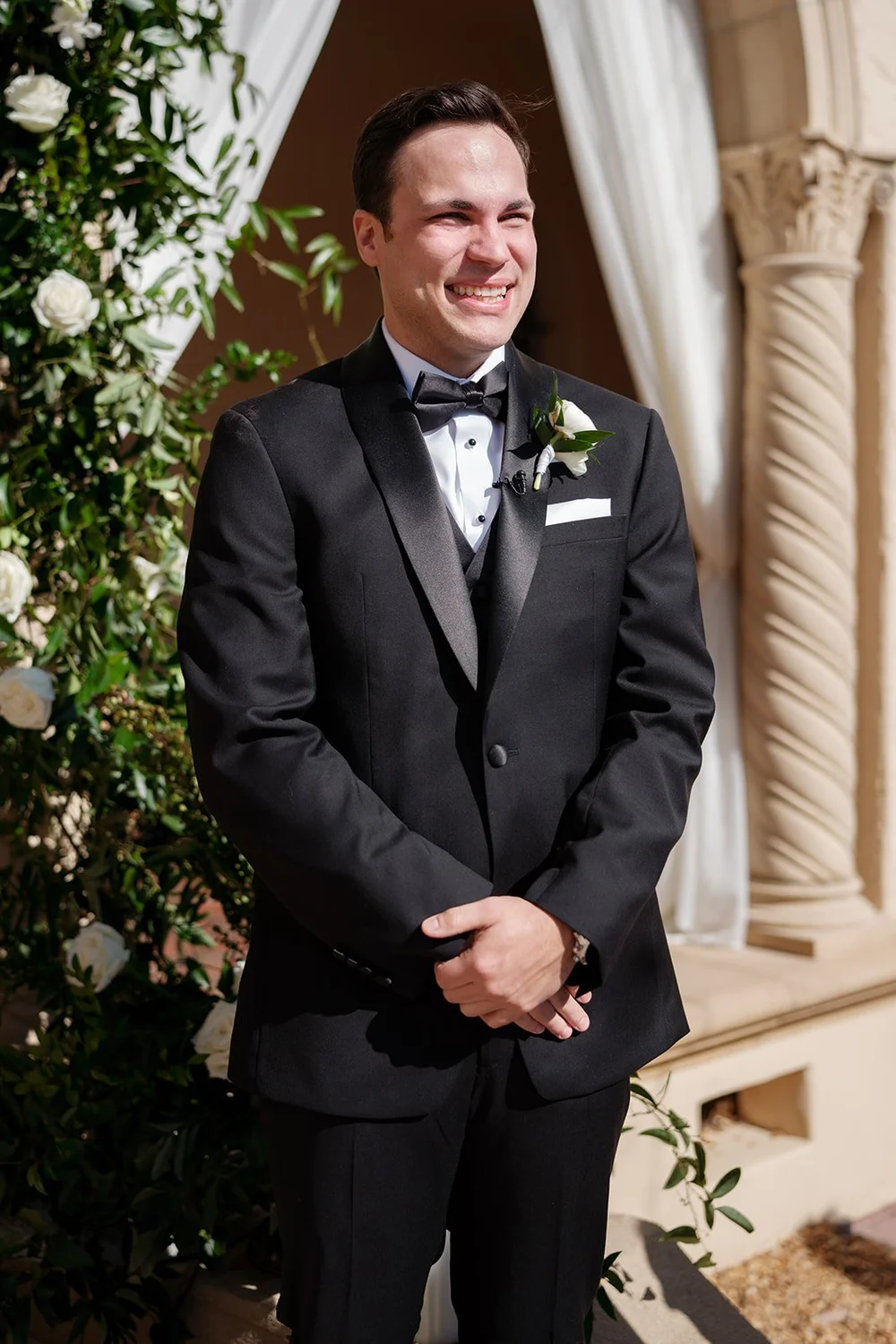 Berkeley standing at the end of the aisle with his hands clasped and a smile on his face