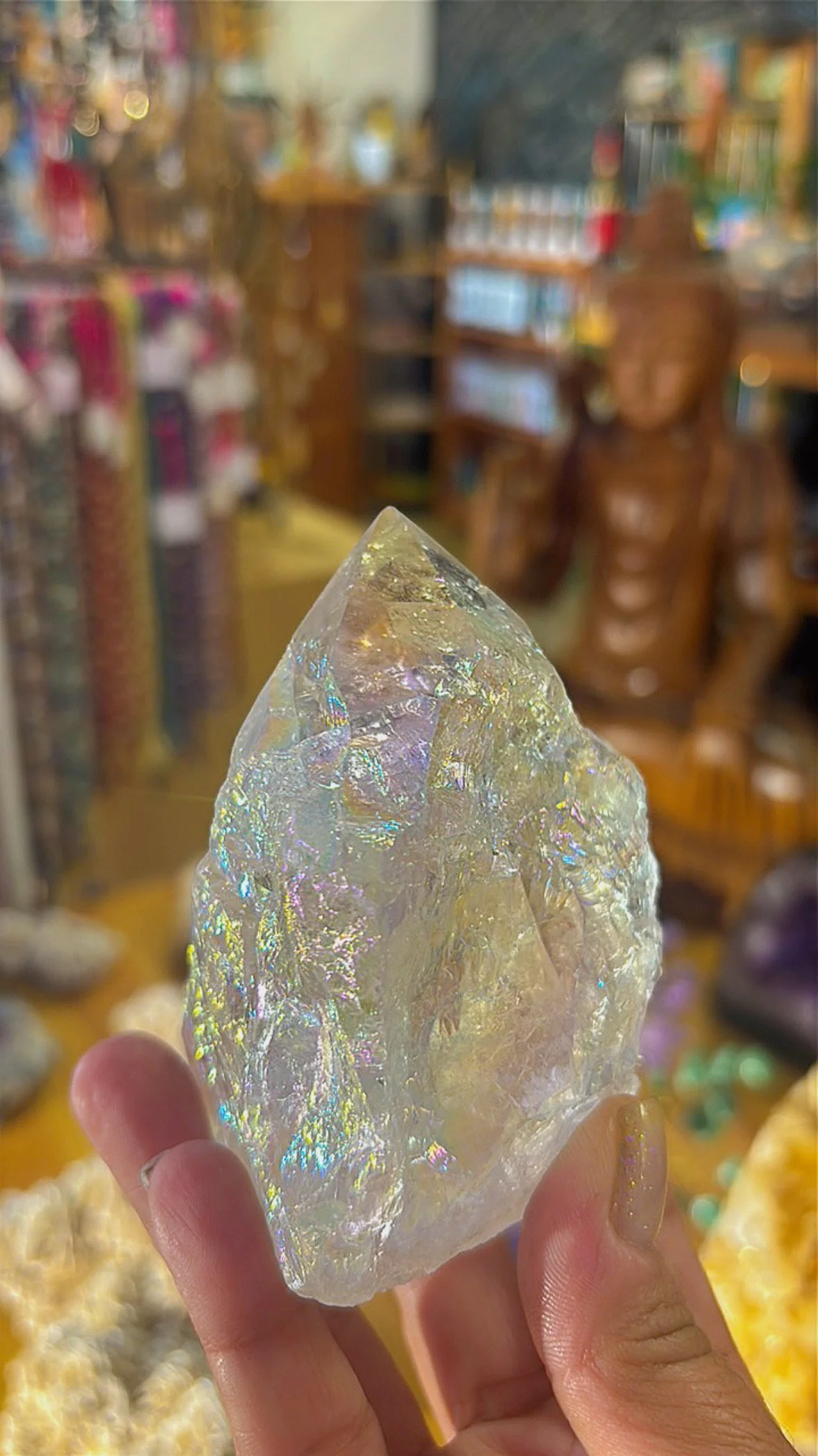 Angel Aura Quartz point with shimmering rainbow surface, held in hand inside Soul II Soul store.