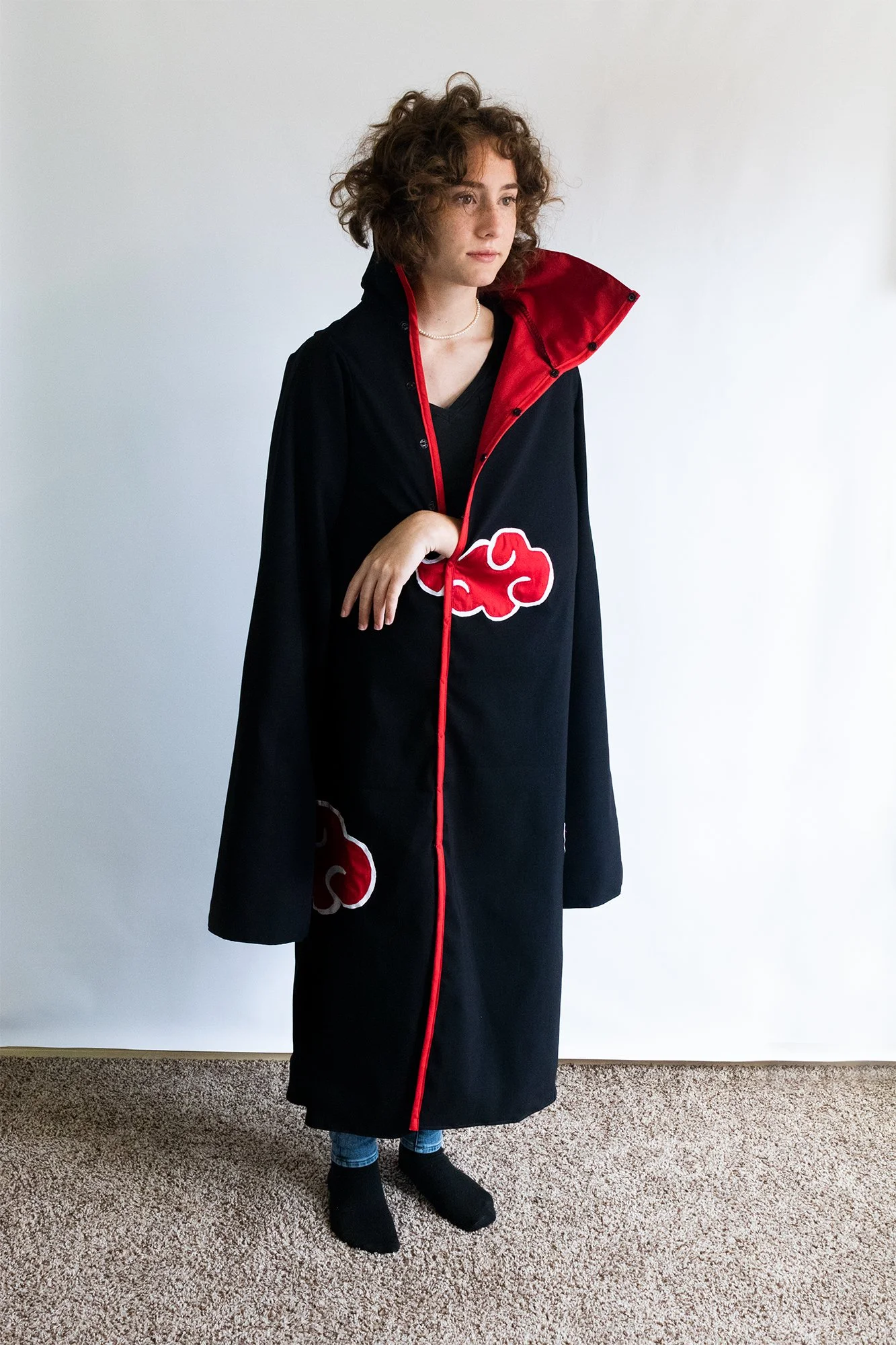 A high-quality Akatsuki robe cosplay from Naruto by Tiffany Gordon Cosplay, featuring black fabric with red cloud patches, a high red collar, and red piping.