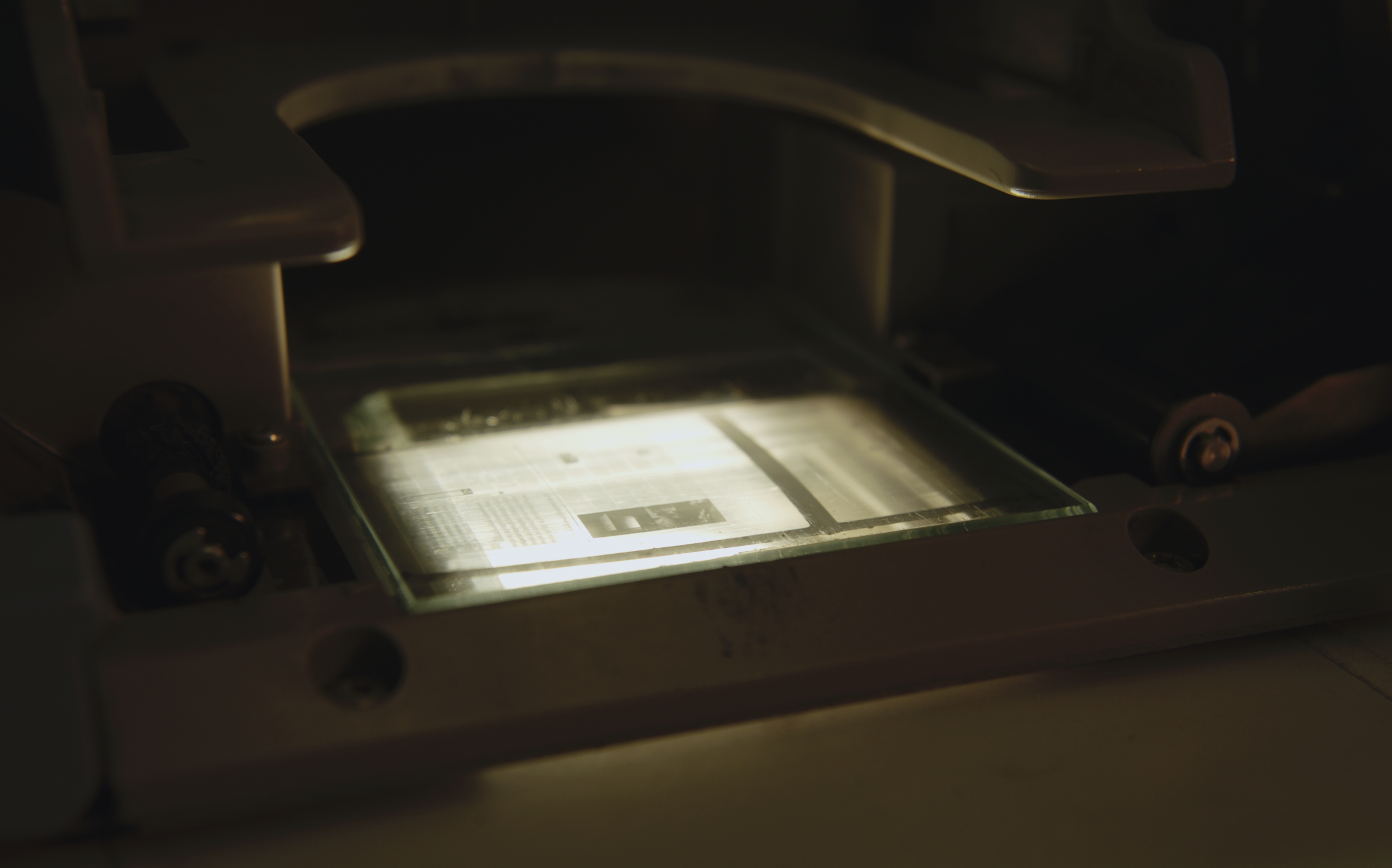Close-up of a lightbox with an illuminated microchip or circuit board inside, surrounded by a dark environment