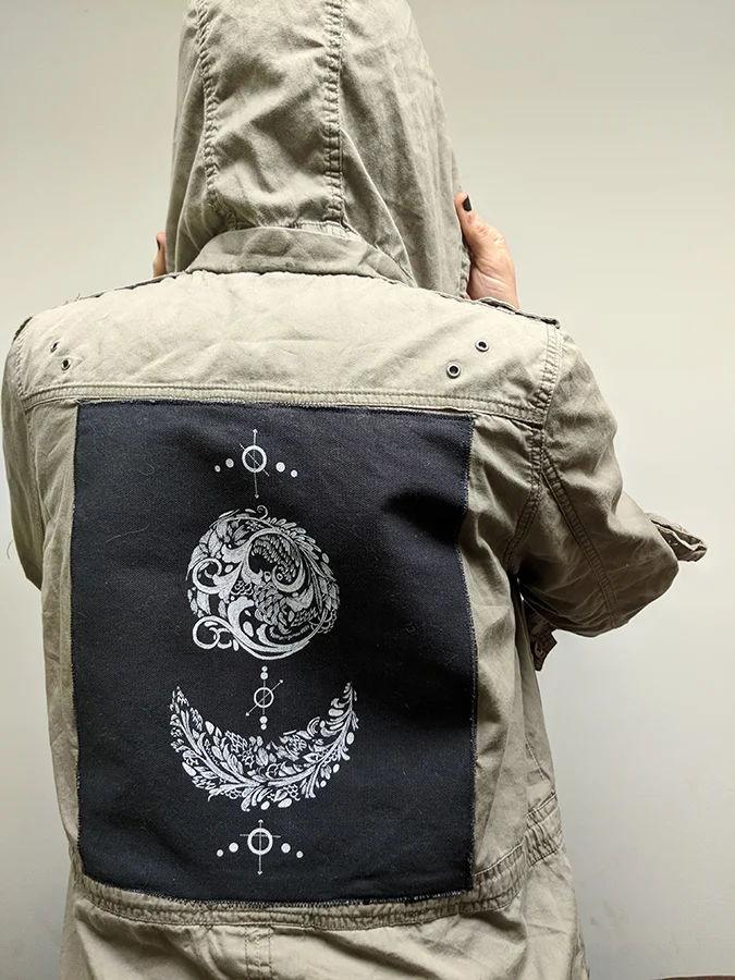 Slant Press homepage image featuring a screen printed pactch affixed to the back of a green military jacket.