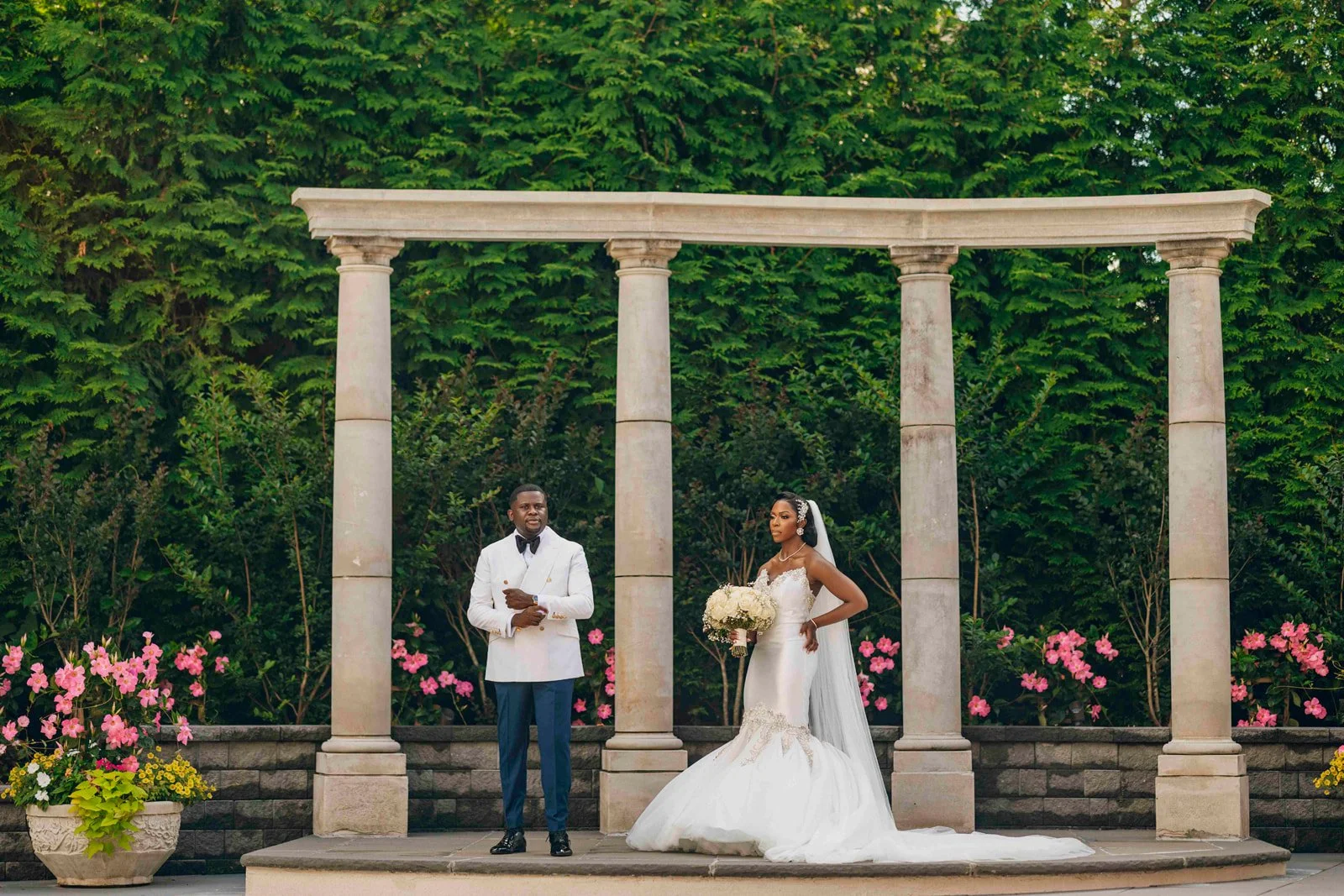Bride and groom standing beneath a stone colonnade, photographed by Topflash Photography