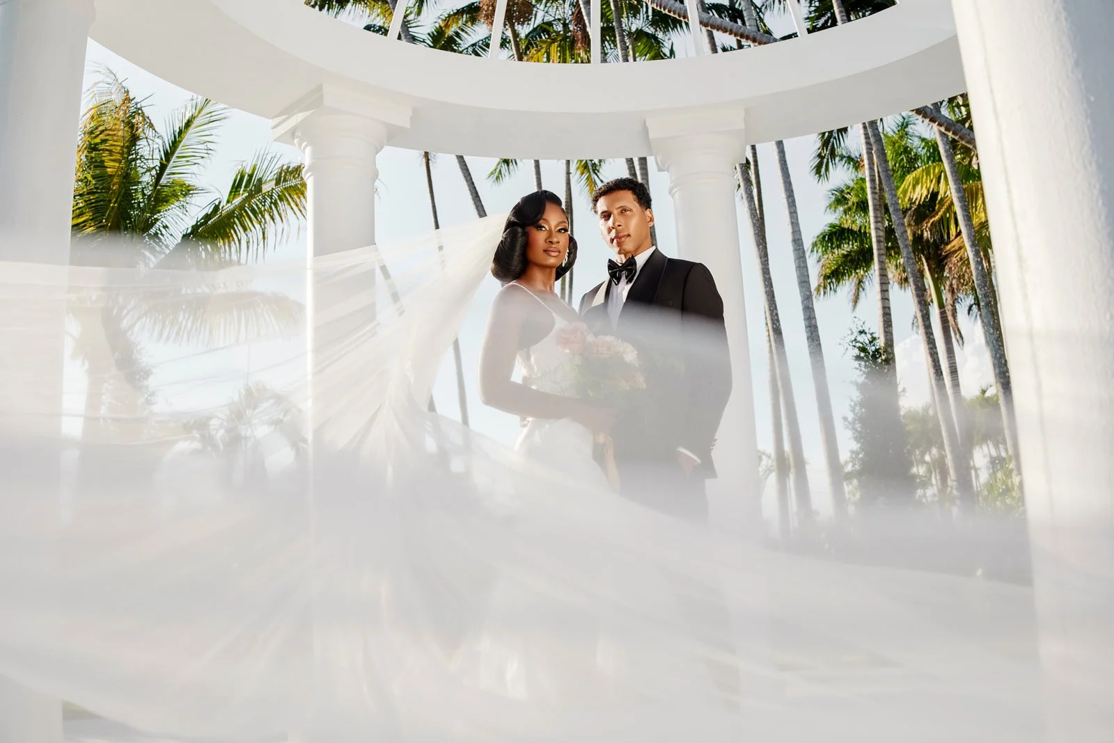 Bride and groom standing among white floral wedding decor, photographed by Topflash Photography