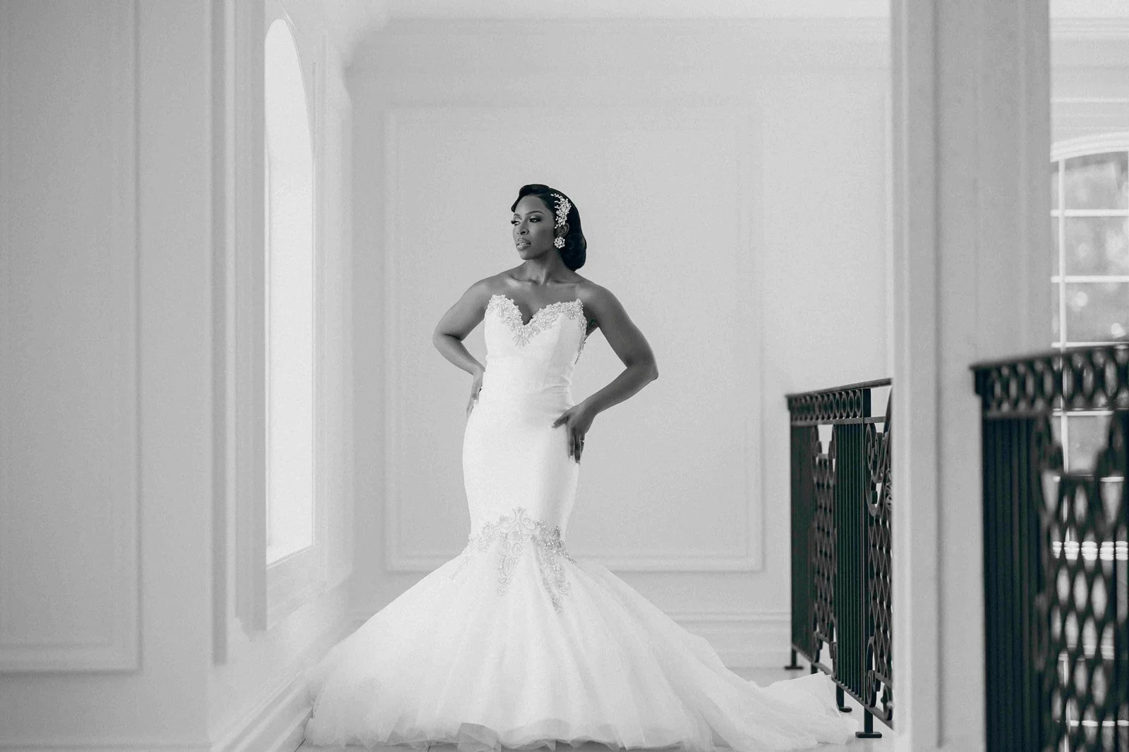 Black and white portrait of a bride in a wedding gown near a window, photographed by Topflash Photography