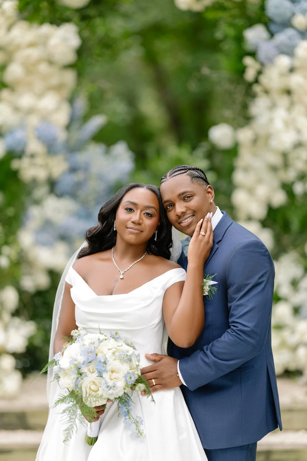 Bride and groom in a navy suit among white and blue florals, photographed by Topflash Photography