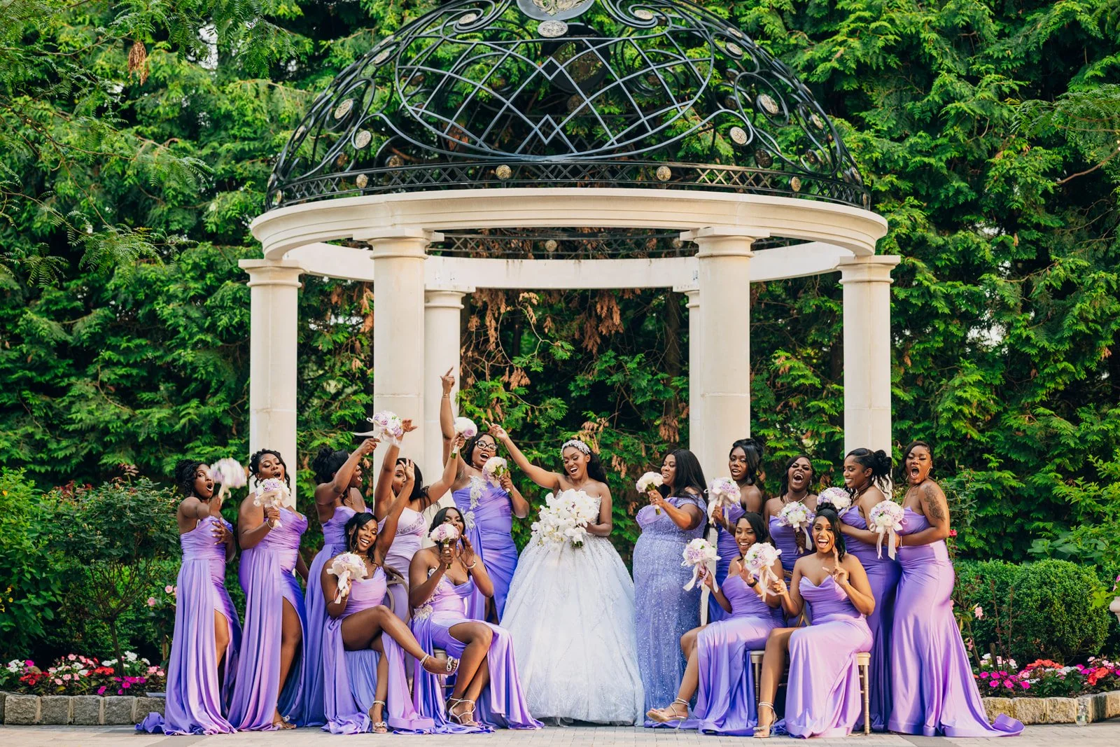 Bride with bridesmaids in lavender gowns beneath a garden gazebo, photographed by Topflash Photography
