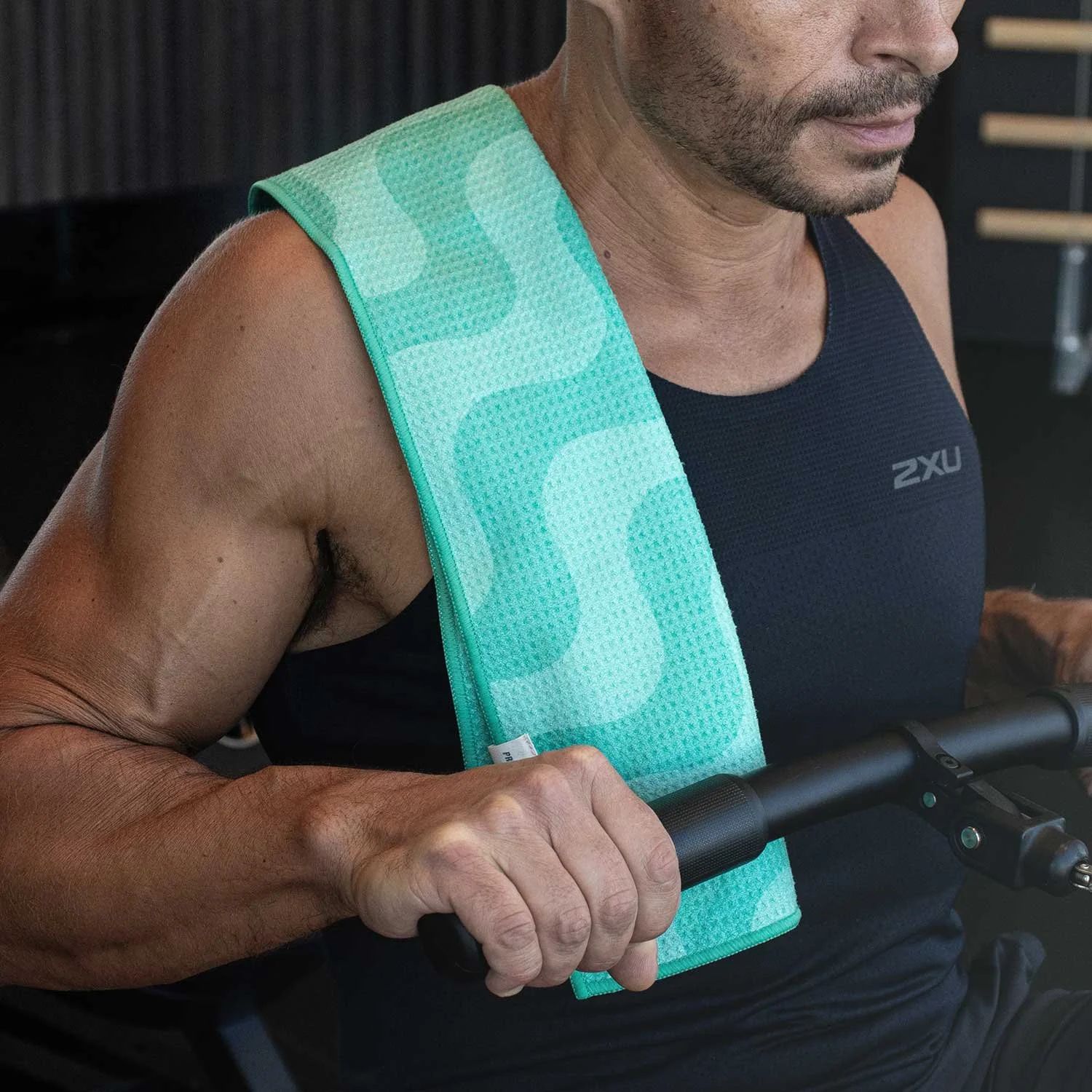 Pro-Dri odour-resistant towel for Aussie gym workouts. Male rowing on a gym machine with Pro-Dri towel neatly draped over his right shoulder.