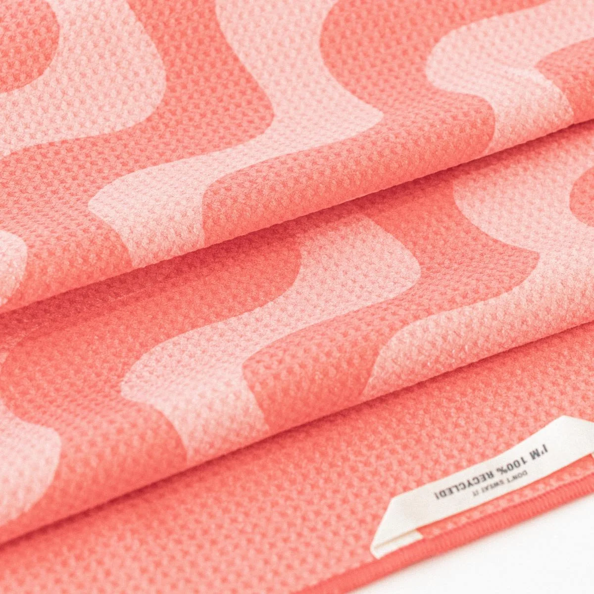 Close up image of the Pro Dri towel material. Coral Pink colour is shown, luxurious waffle texture is displayed.