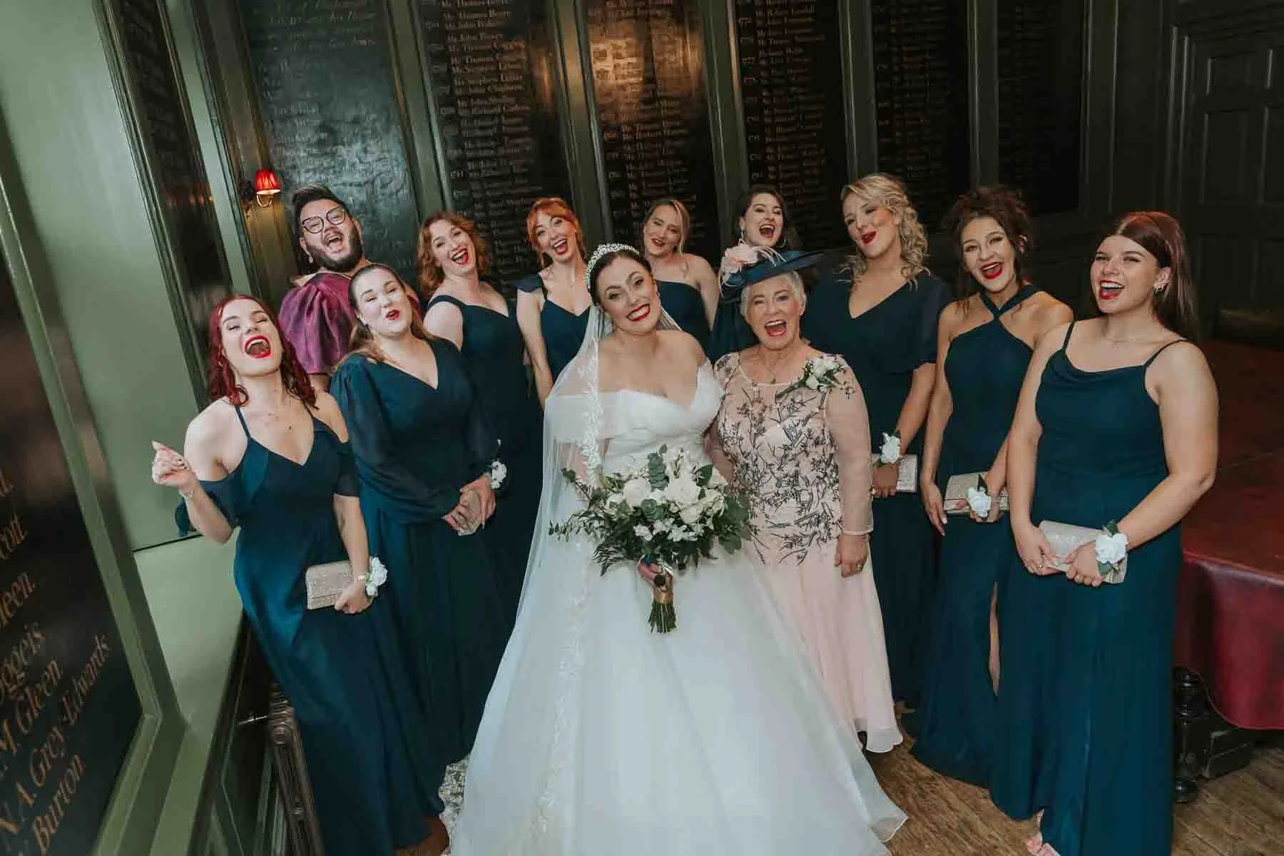 Bride, mother-of-the-bride and entire bridal party pose for a photograph.