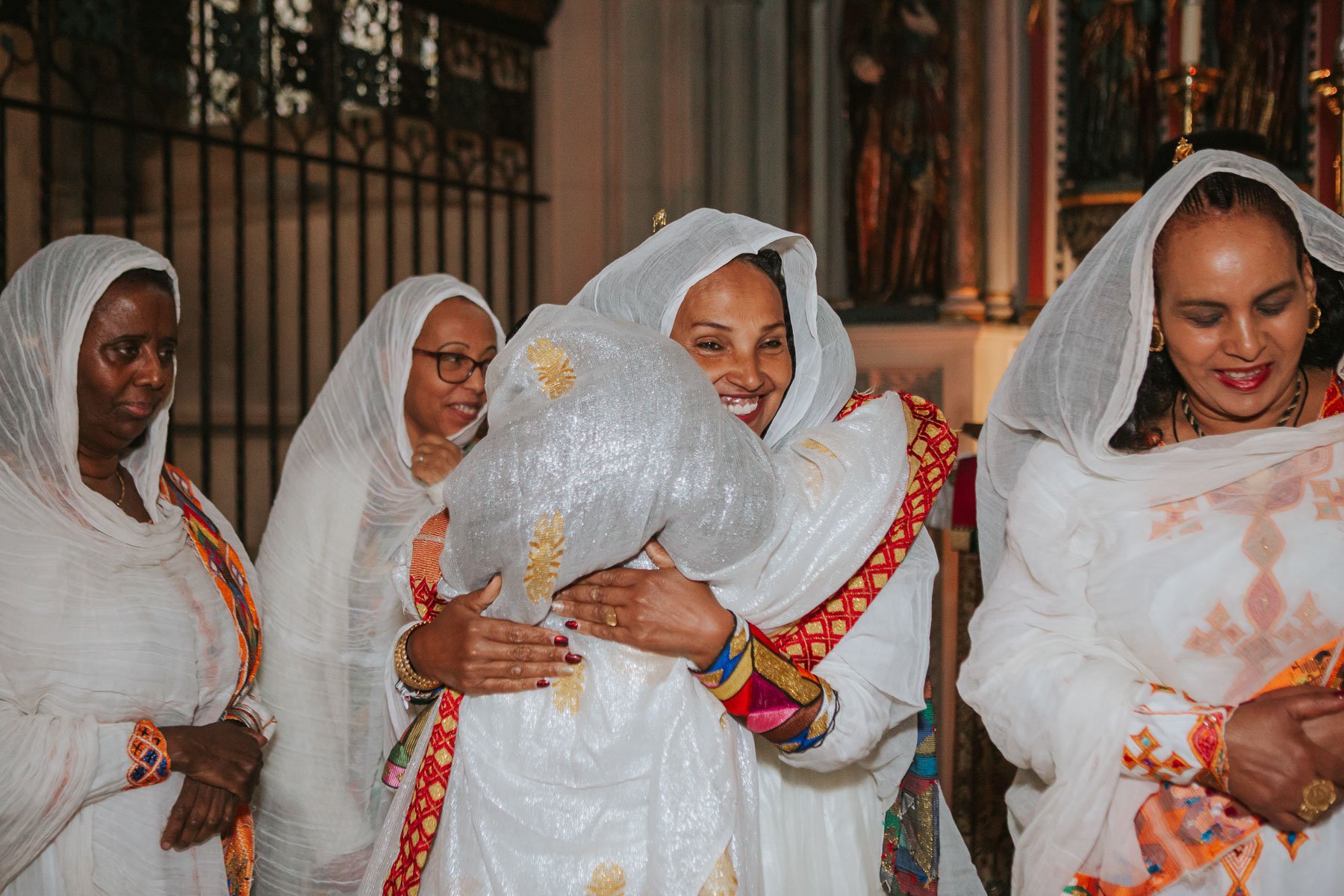 Grandmother of the baby hugs her freinds dressed in traditional Eritrean dress.