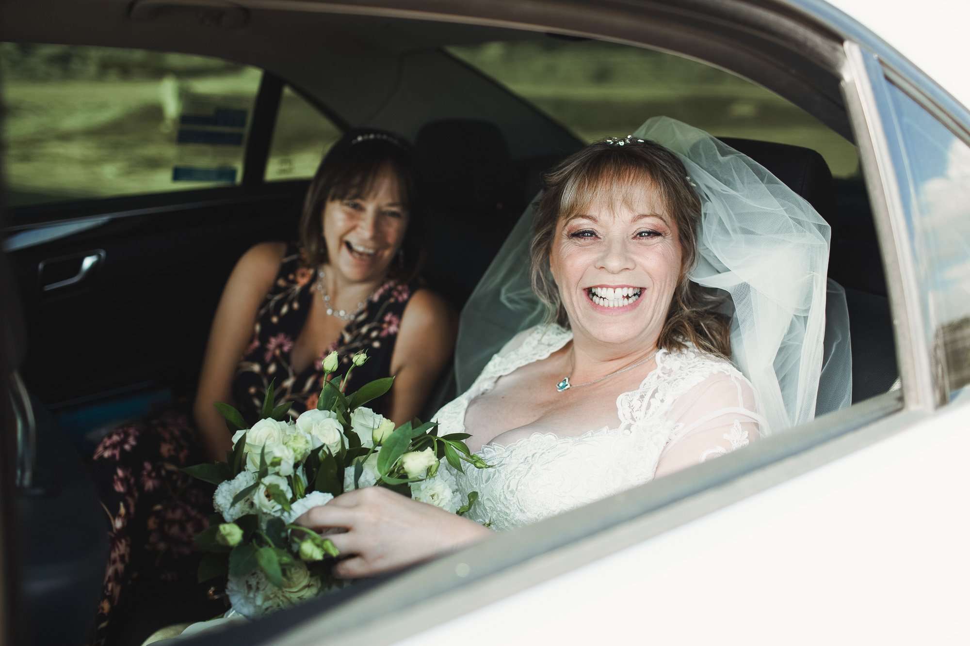 Bride arriving in car with bridesmaid