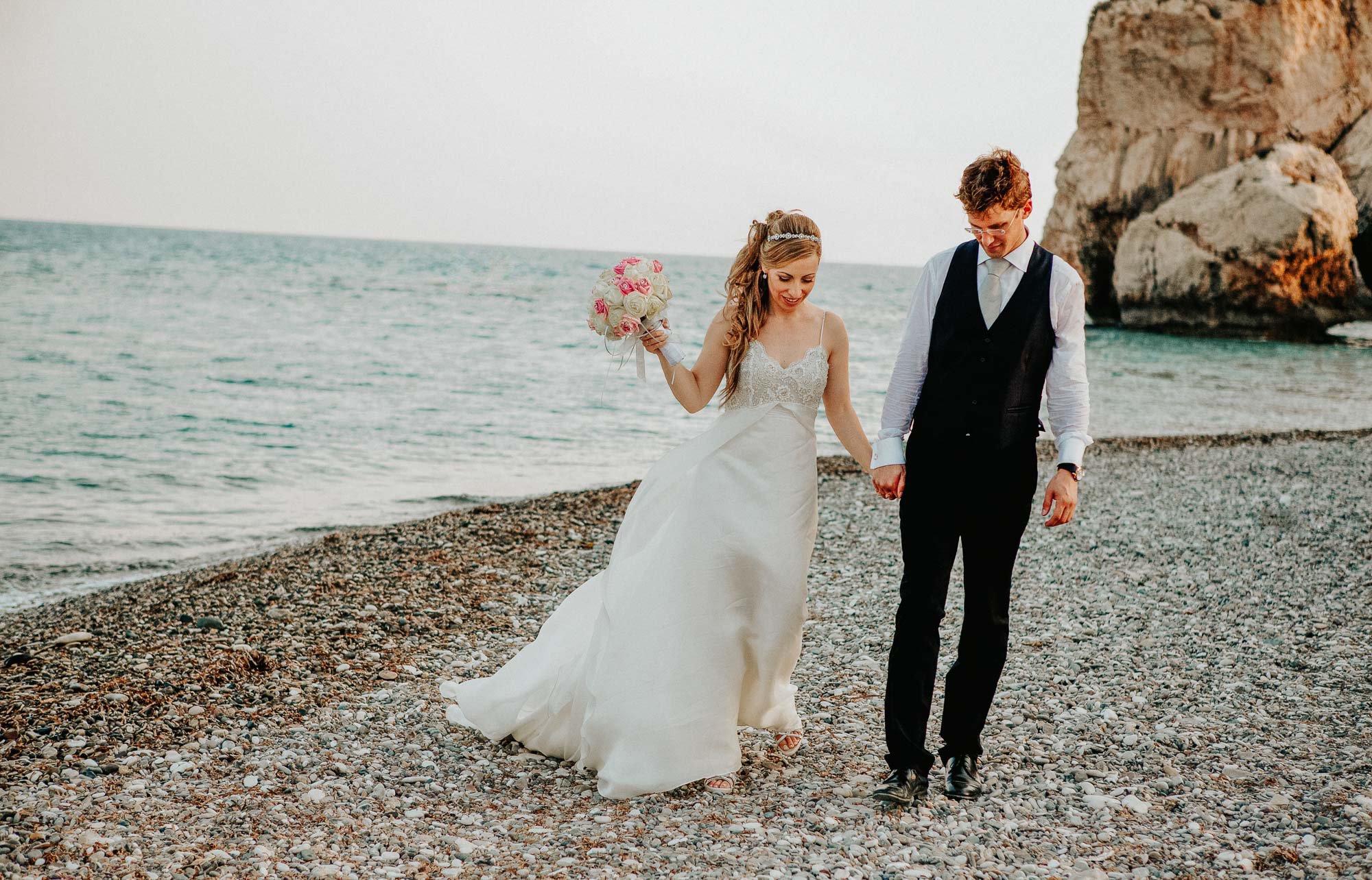 Married couple walking hand in hand by Aphrodites Rock (Petra tou Romiou) Cyprus.