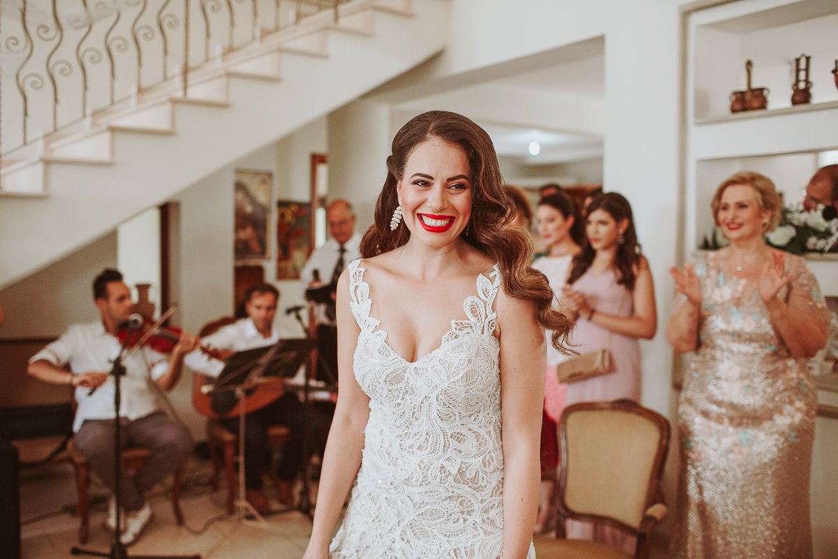 Bride at her stolisma with musician playing violin in the background.