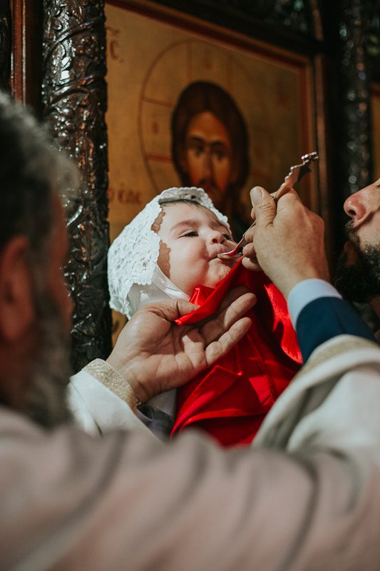 Baby receiving holy communion in the greek orthodox church.