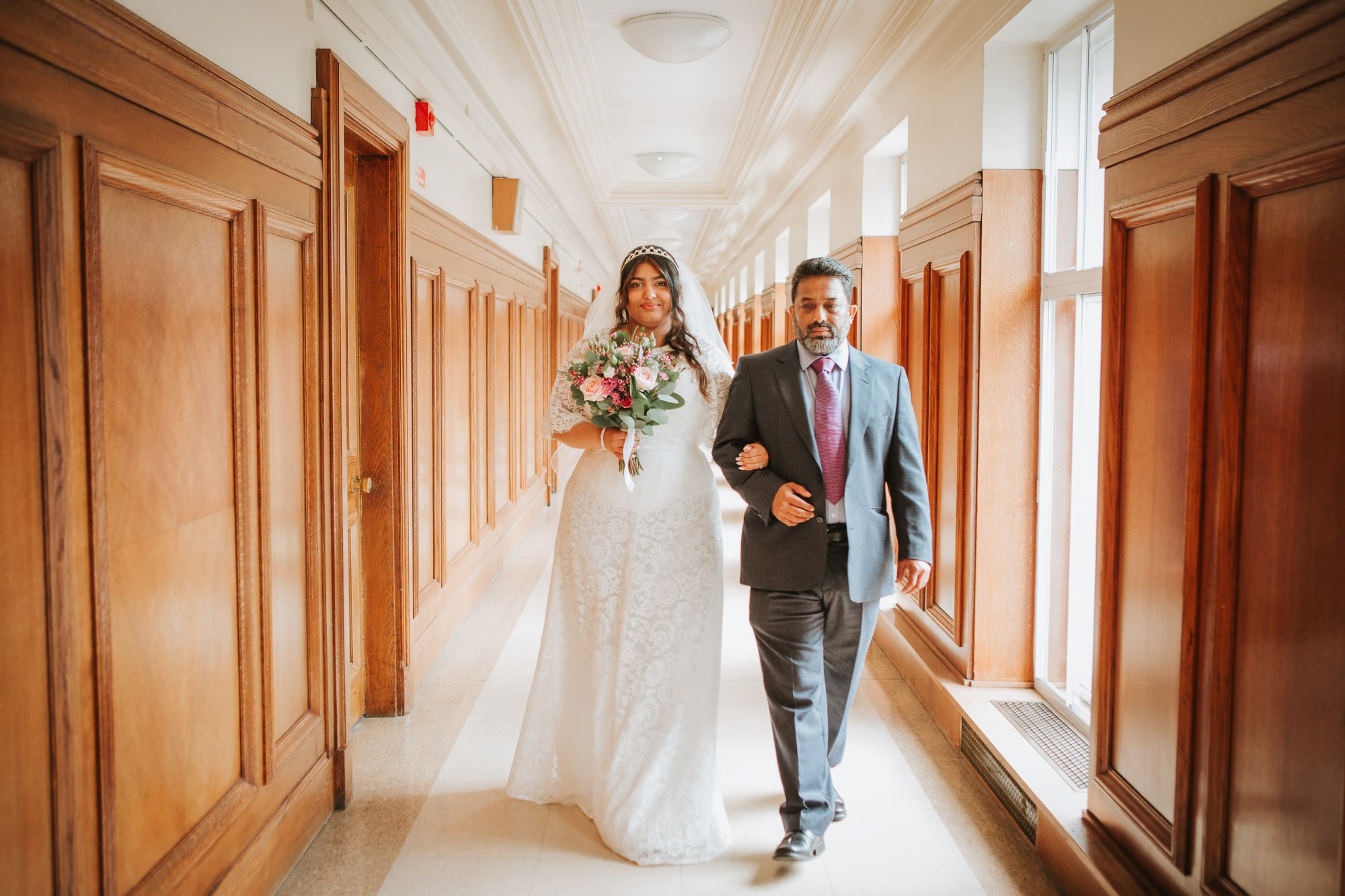  Bride walking down the corridor with her father, at Wandsworth Town hall. 