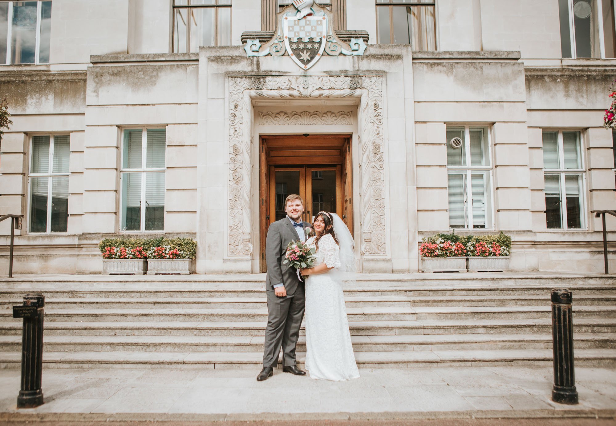  Newly married bride and groom posing outside on the steps at Wandsworth Town Hall. 