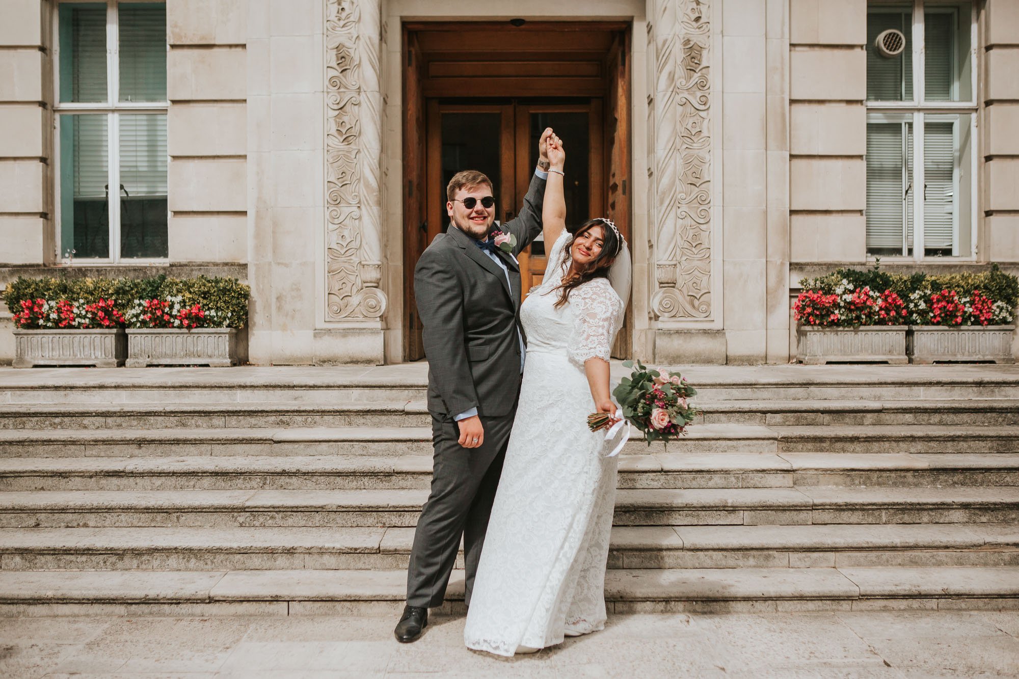  Newly married bride and groom posing outside on the steps at Wandsworth Town Hall. 