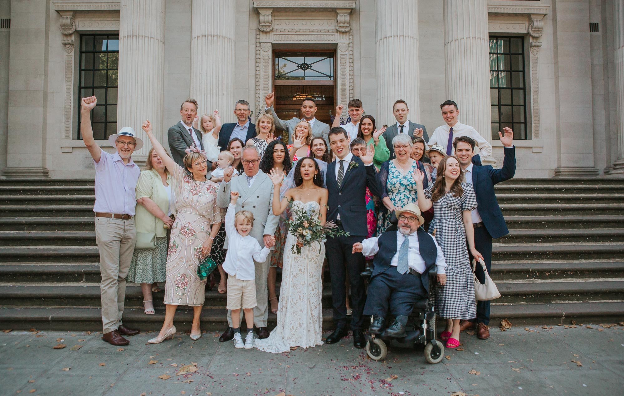  Groom and bride posing with their friends and family outside Marylebone Town Hall in Marylebone, London.   